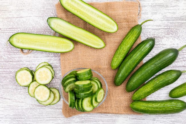 top-view-cucumber-sliced-glass-bowl-beige-linen-bag-white-wooden-horizontal