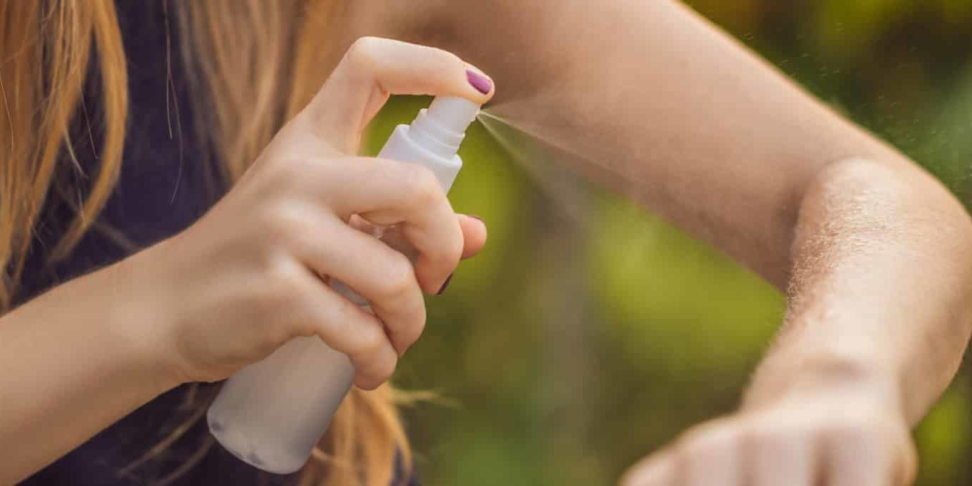 Woman spraying insect repellent on skin outdoor BANNER, LONG FORMAT