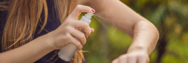 Woman spraying insect repellent on skin outdoor BANNER, LONG FORMAT